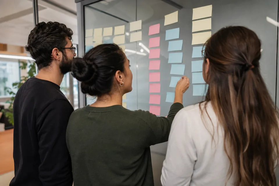 Team arranging sticky notes on a glass wall