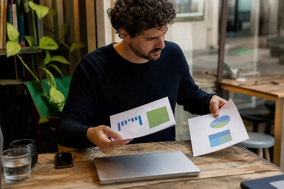Founder comparing printed metrics at a cafe table