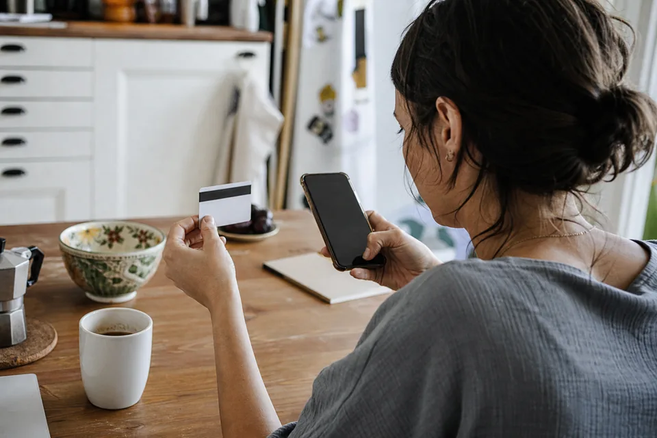 Customer entering card details on a phone at a kitchen table
