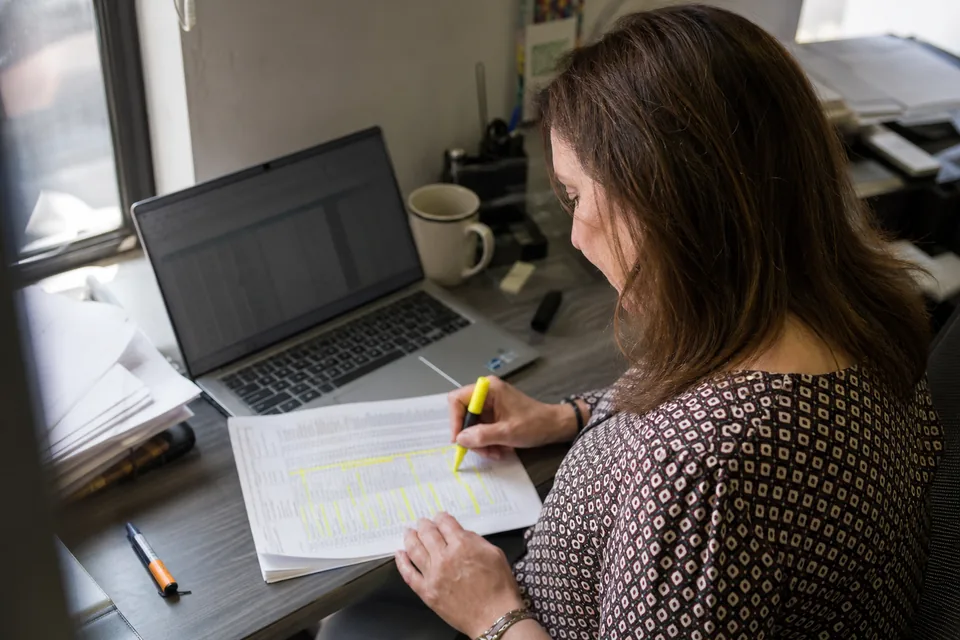 Analyst highlighting rows on printed invoices