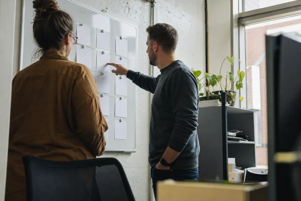 Customer success managers reviewing account cards on a whiteboard