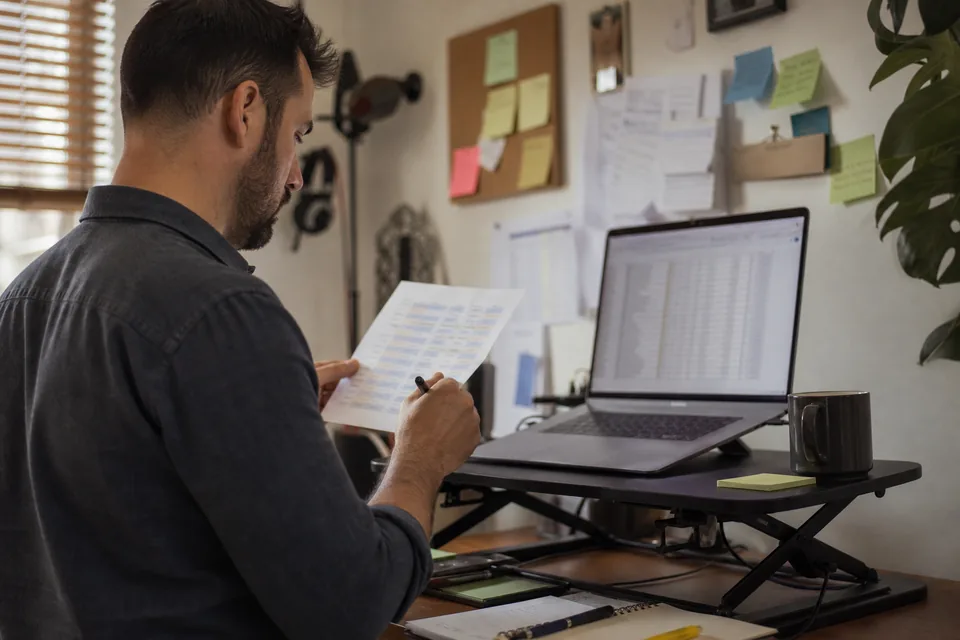 Operations lead comparing a printed renewal list with a laptop