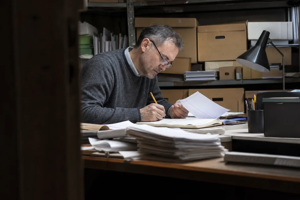 Auditor checking printed invoices against a ledger